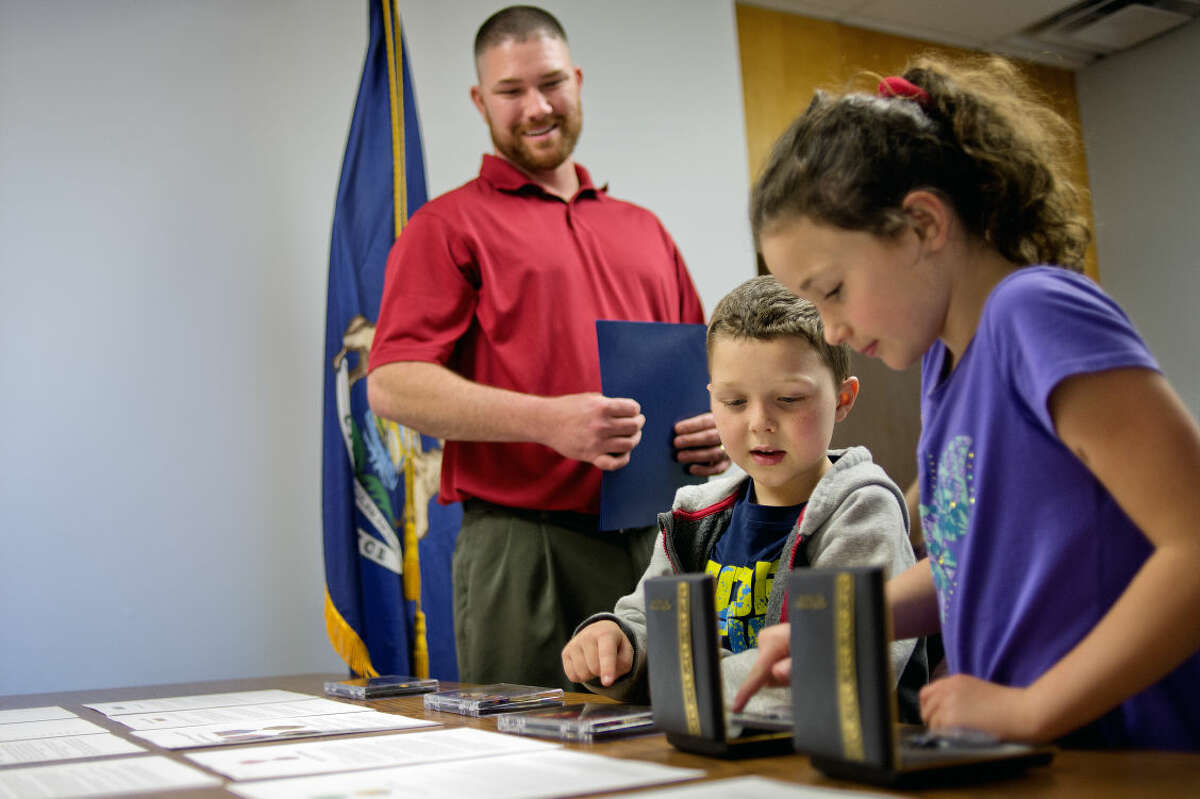 Army veteran Micheal Tacey, of Bay City, left, looks on as two of his children Ethan, 6, center, and Lilianna, 7, look at their father's military medals after a presentation ceremony on Monday at U.S. Rep. John Moolenaar's Midland office.