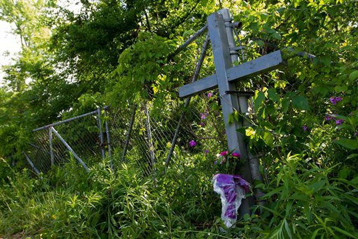 A cross and flowers are placed in lieu of a memorial at the the scene of a fatal crash that happened Tuesday evening involving several bicyclists in Cooper Township, Mich., on Wednesday, June 8, 2016. Several people were killed and others were seriously injured. (Bryan Bennett/Kalamazoo Gazette-MLive Media Group via AP) LOCAL TELEVISION OUT; LOCAL RADIO OUT; MANDATORY CREDIT