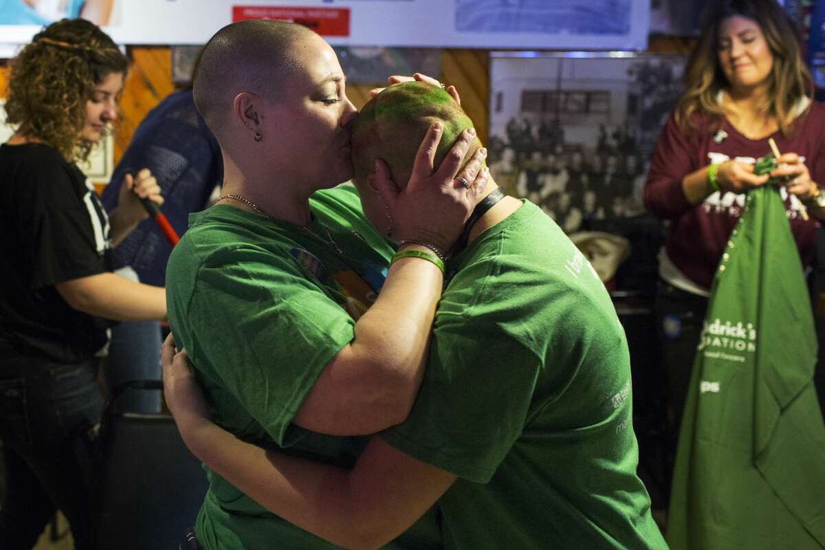 Michelle Schuch of Bay City, EMS Dispatcher for MidMichigan Medical Center-Midland, left, places a kiss on the freshly shaven head of her daughter, Adrienne Befell, 12, right, after having their heads shaved during a fundraiser at The Boulevard Lounge on Saturday.