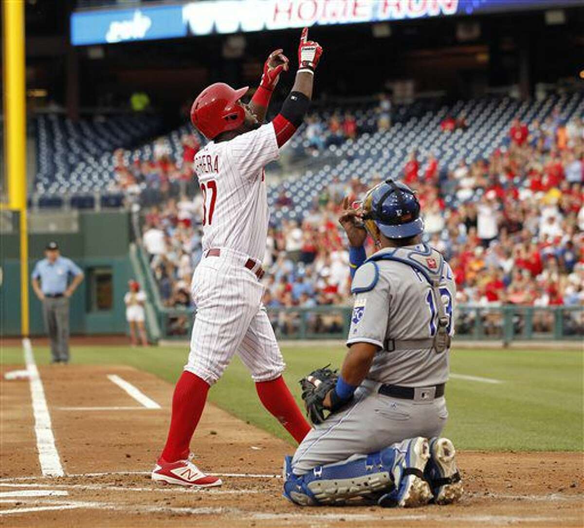 Philadelphia Phillies' Odubel Herrera, left, points skyward as he walks past Kansas City Royals catcher Salvador Perez after hitting a solo home run during the first inning of a baseball game Friday, July 1, 2016, in Philadelphia. (AP Photo/Tom Mihalek)