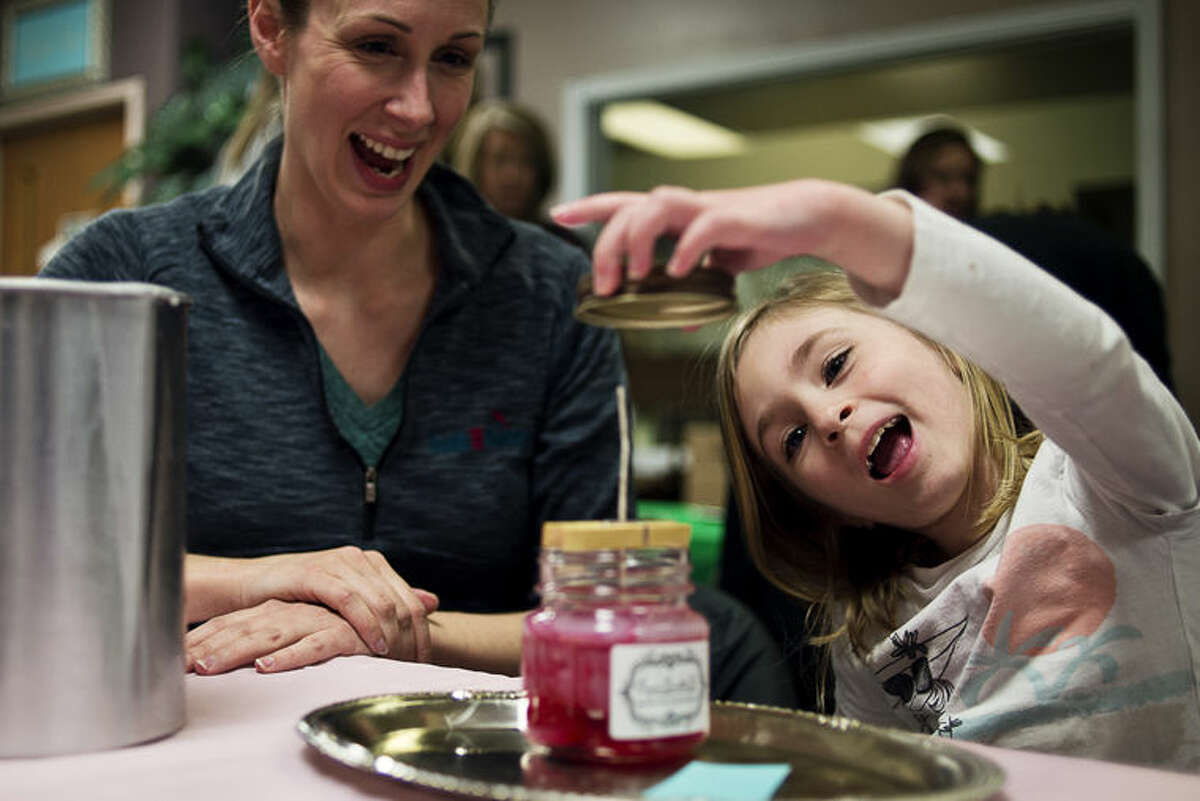 Midland resident Kristin Conkright, left, watches as her daughter Emily Conkright, 5, smiles while waiting for her candle wax to form during a candle making class at Coyer Candle Co.