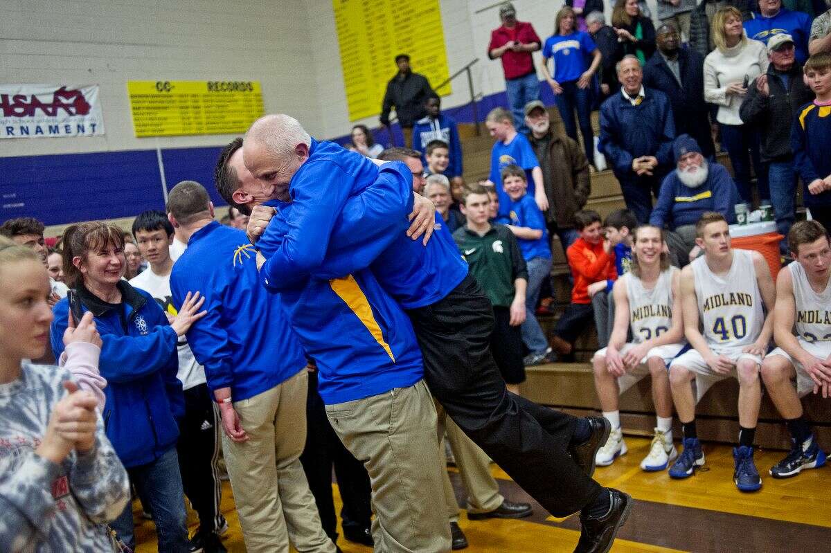 Midland assistant coach Scott Robertston lifts head coach Eric Krause after their team's victory over Saginaw on Wednesday at Bay City Central High School. The Chemics beat the Trojans 60-56, winning their first Class A regional basketball championship in 37 years.
