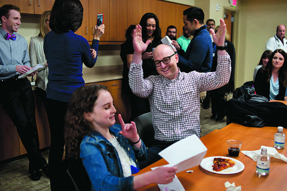  Fourth-year Michigan State University College of Human Medicine student Seth Simpson, center, raises his hands in celebration as his daughter Ella Simpson, 10, both of Midland, announced that he matched into the triple board residency program at Cincinnati Children's Hospital Medical Center on Friday afternoon at the MidMichigan Medical Center Gerstacker Building. Simpson along with eight other Midland Regional Campus fourth-year medical students found out what residency programs they matched with. Cincinnati was Simpson's top choice where he'll do a 5 year residency focusing on pediatrics, psychiatry, and child psychiatry. "It's awesome," Simpson said. "But nerve racking to know that I'm starting my residency."