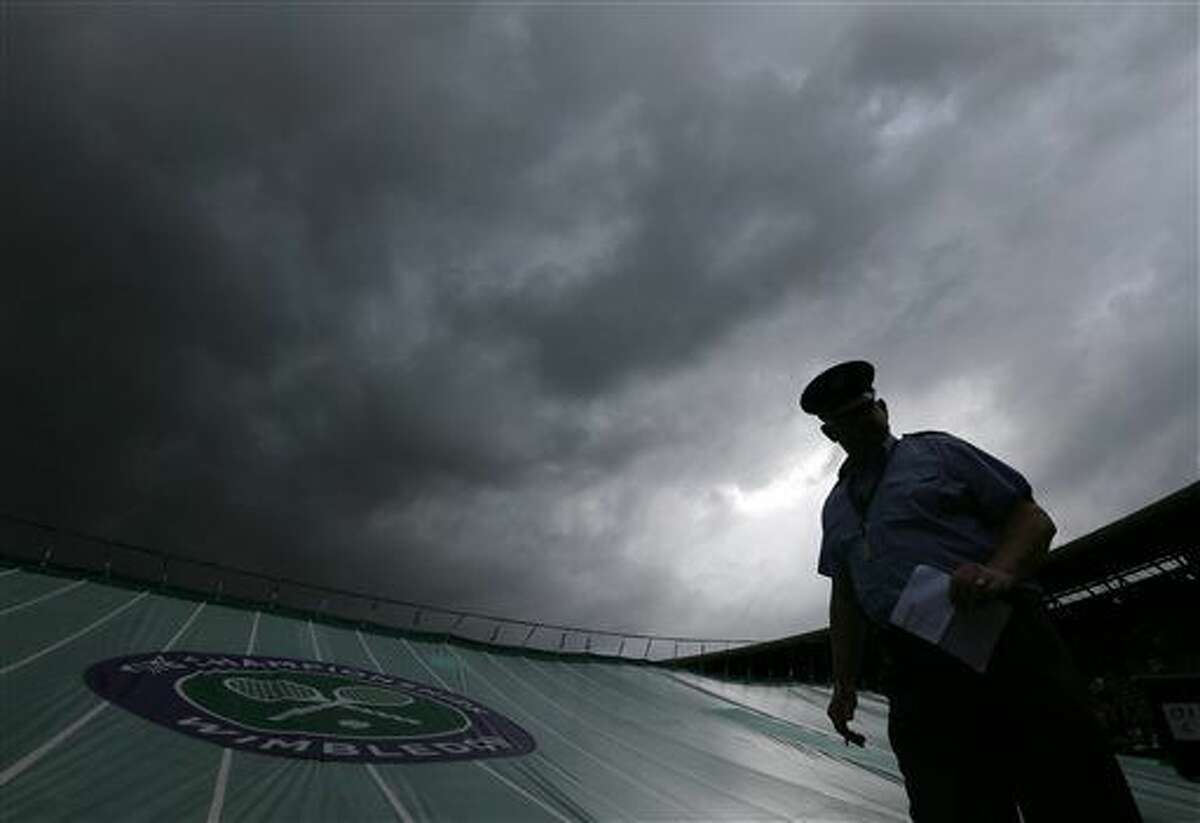 A member of staff stands by a covered out as rain delays play during day five of the Wimbledon Tennis Championships in London, Friday, July 1, 2016. (AP Photo/Tim Ireland)