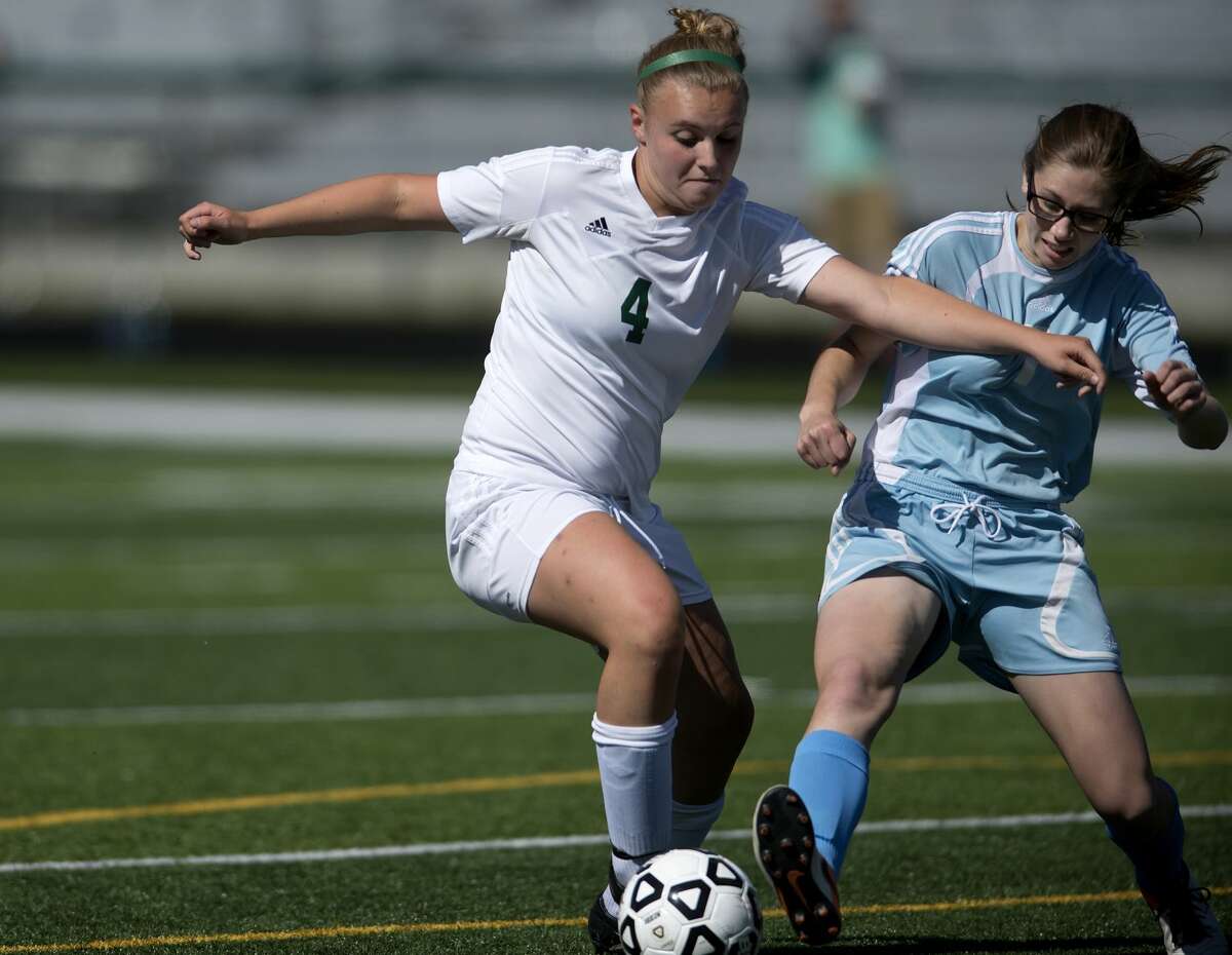 Freeland High School's Mackenzie Stroebel, left, works to keep the ball away from TC Liberty's Angie Polomsky in the first half of a Division 3 regional semifinal soccer game on Wednesday in Clare. Freeland defeated TC Liberty 4-1.