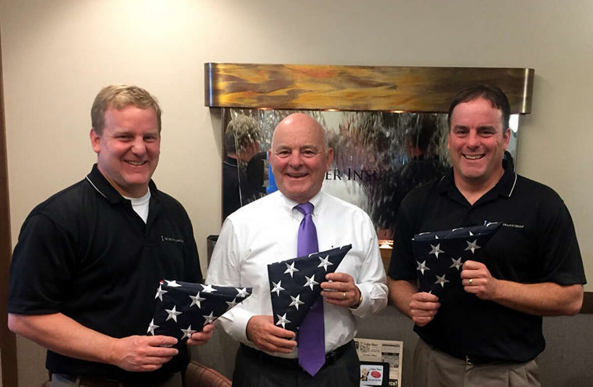 Karl, Cal and Kurt Ieuter are shown with the flags the business is giving away.