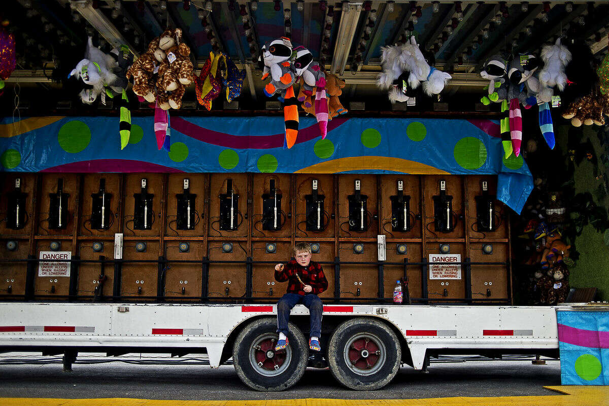 Jack Fitzgerald, 7, son of the owners of the Maple Leaf Amusements carnival, whittles a stick while sitting on a carnival booth during set up on Wednesday evening. The carnival, which will open Friday and remain until April 24, is located at the intersection of Washington Street and Saginaw Road.