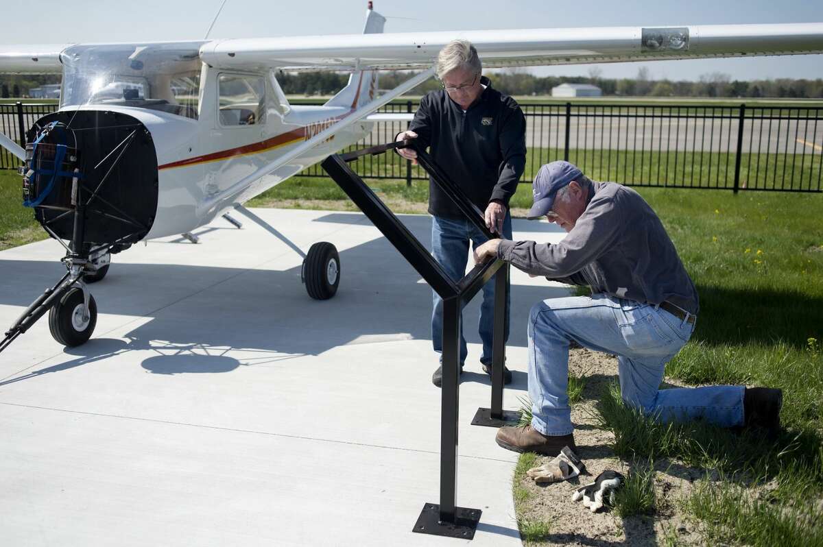 Jim Cordes, left, and Matt Jansen position display boards that will hold aviation educational information in front of the life-size model airplane at the Midland Community Aviation Discovery Area at Barstow Airport.