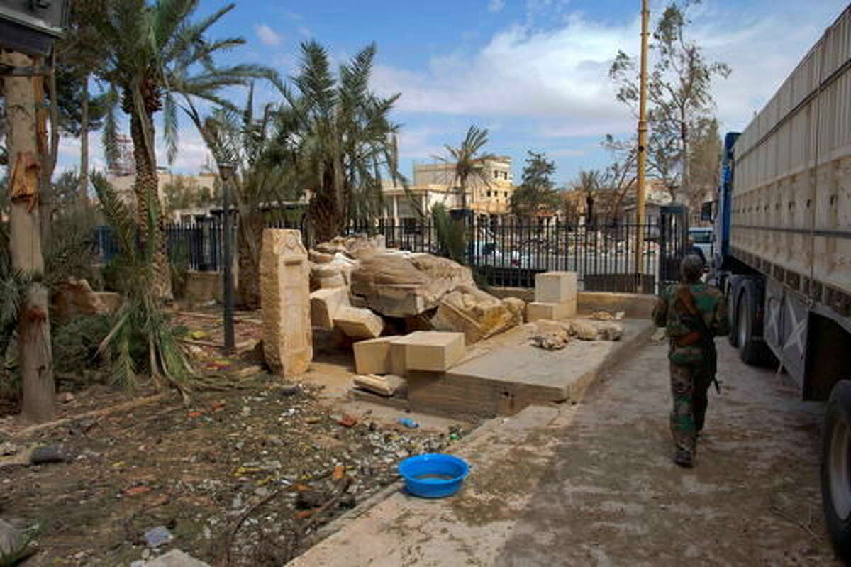In this Thursday, April 14, 2016 photo, A Syrian soldier walks next to the damaged Lion of Al-Lat statue outside the museum with some broken pieces lying next to it at the entrance of the museum in the town of Palmyra in the central Homs province, Syria. Polish experts back from assessing damage at the museum in the Syrian town of Palmyra offer grim new details about the extent of the destruction caused by the Islamic State group. The museum was trashed and some of its best-known artifacts and statues were smashed by the extremists during the 10 months they controlled the town, before being driven out last month. (AP Photo/Hassan Ammar)