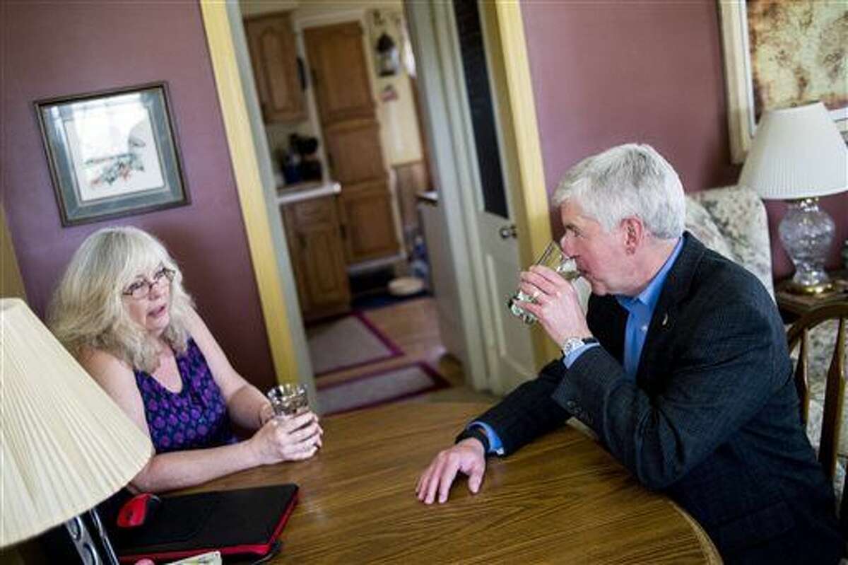 Michigan Gov. Rick Snyder, right, drinks filtered Flint, Mich., tap water with Flint resident Cheryl Hill while listening to her concerns with the city's ongoing water crisis at her home Monday, April 18, 2016. Gov. Snyder says he will drink Flint's water for roughly a month to show residents it is safe. (Jake May/The Flint Journal-MLive.com via AP) 