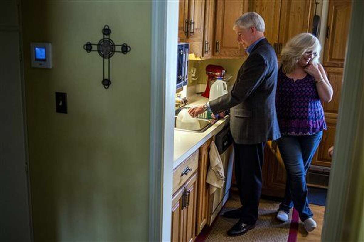 Michigan Gov. Rick Snyder, left, fills jugs with filtered Flint, Mich., tap water alongside Cheryl Hill at Hill's house where he drank his first glass of the local water Monday, April 18, 2016, on the city's east side. Gov. Snyder says he will drink Flint's water for roughly a month to show residents it is safe. (Jake May/The Flint Journal-MLive.com via AP) 