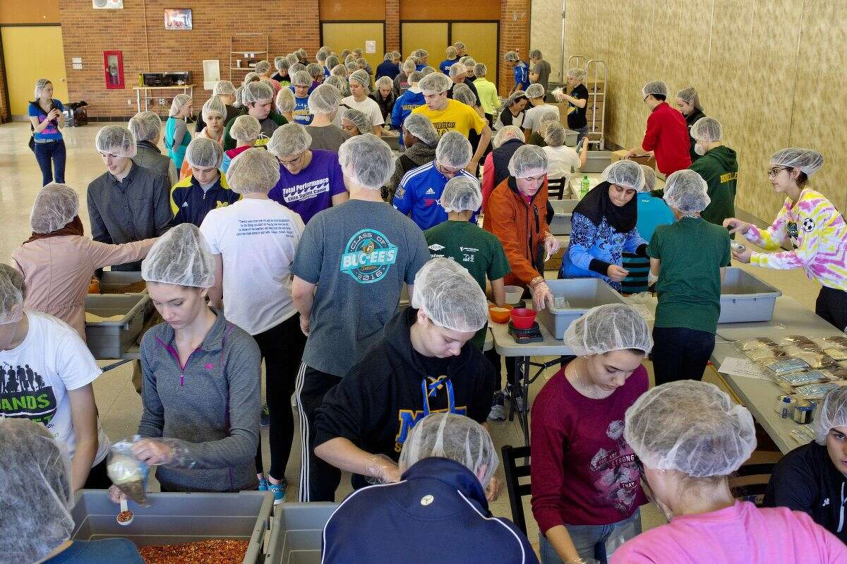 Hundreds of students from Midland and Dow high school work to fill meal bags on Saturday in the Dow High School cafeteria.