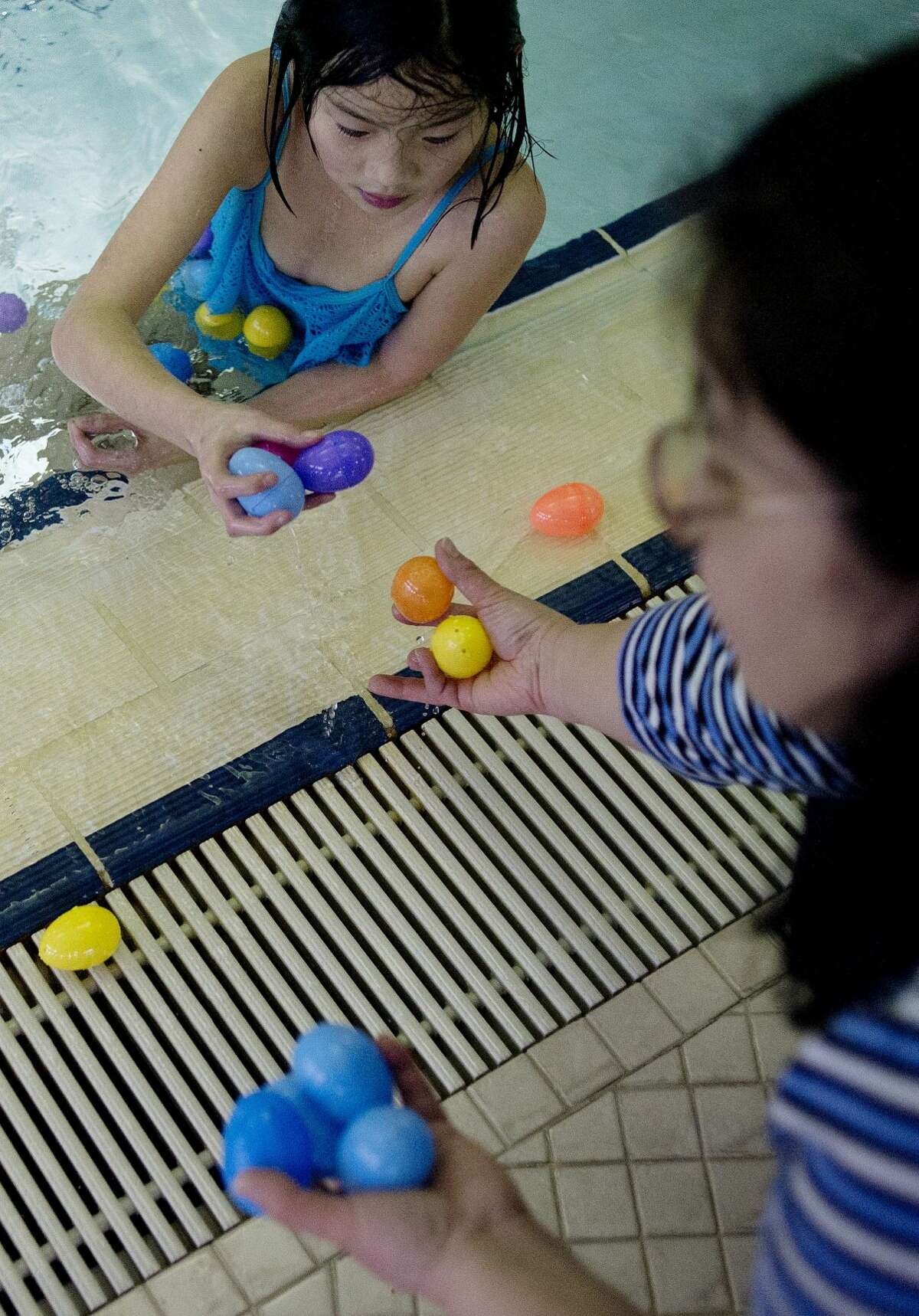 Eleven-year-old Megumi Togashi, top, hands plastic eggs that she collected to her mother, Toko Togashi, both of Midland, during the Easter Egg Dip at the Greater Midland Community Center.