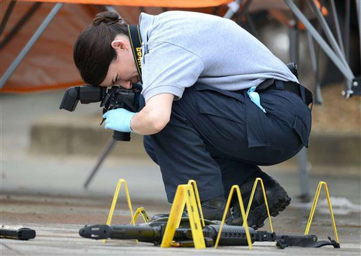 A law enforcement agent photographs the scene of a multiple shooting in Bristol, Tenn., on Thursday, July 7, 2016. Police say multiple people have been injured and one person was taken into custody after a man opened fire on motorists traveling along a parkway in East Tennessee. Bristol police say the incident happend early Thursday in the city along the Virginia border. (David Crigger/The Bristol Herald-Courier via AP)