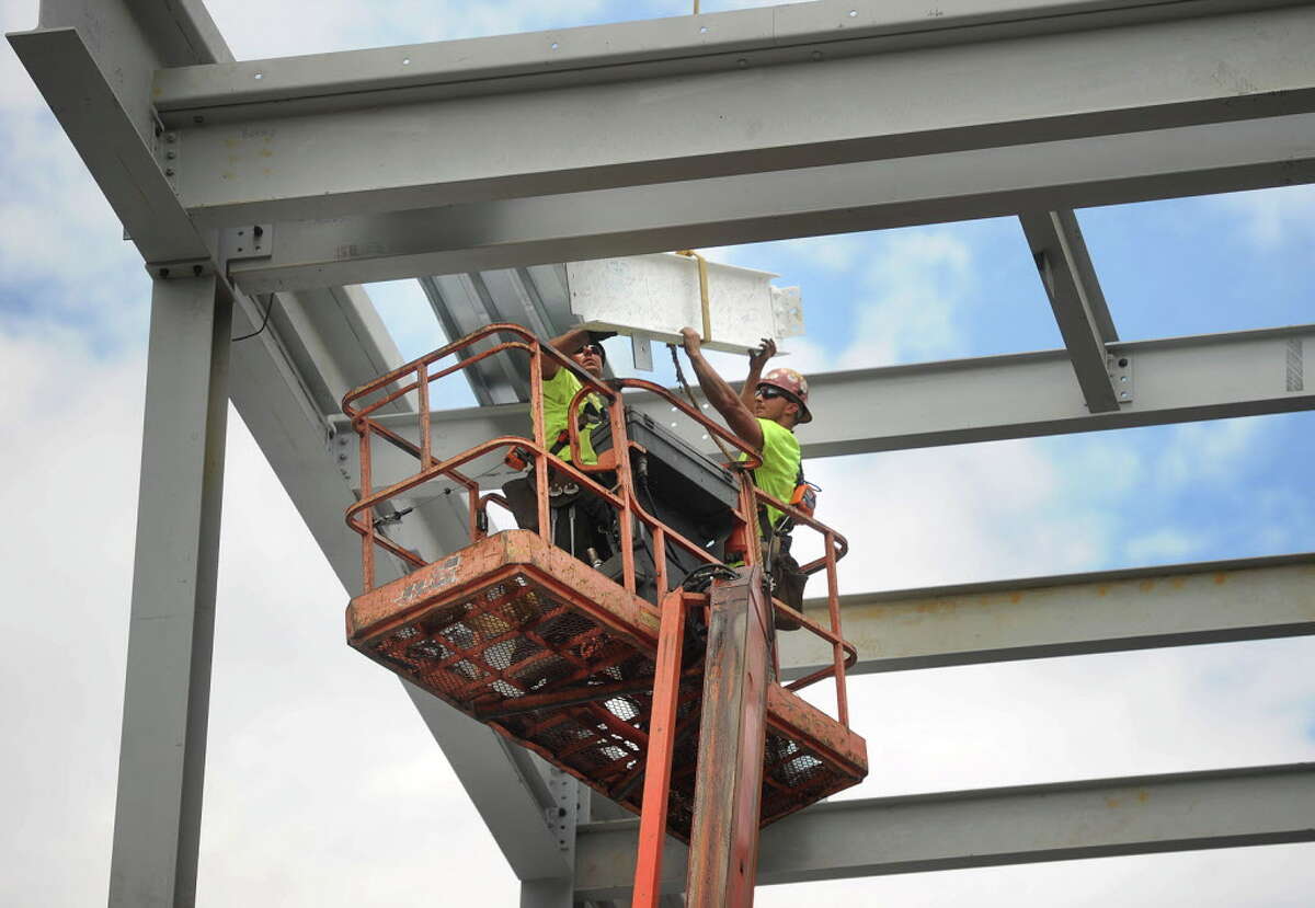The final beam, painted white and signed by members of the Housatonic Community College community, is lowered into place during continued construction on the school's expansion project facing Lafayette Boulevard in Bridgeport, Conn. on Thursday, June 23, 2016. The additions to the school are scheduled to open for use in 2017.