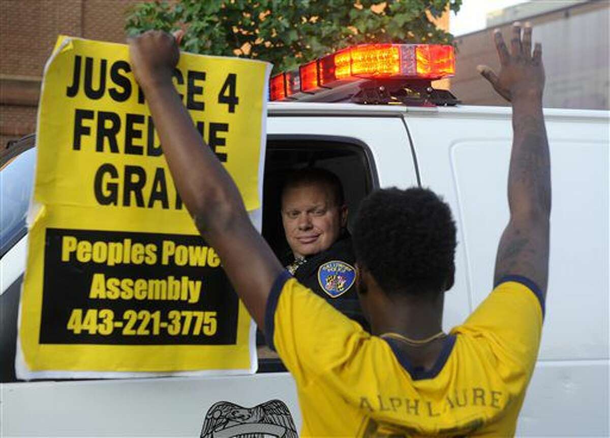 Melvin Townes, of Baltimore, stands with a "Justice 4 Freddie Gray" sign in front of a police officer during a protest Friday, July 8, 2016, in Baltimore. (Caitlin Few/The Baltimore Sun via AP)