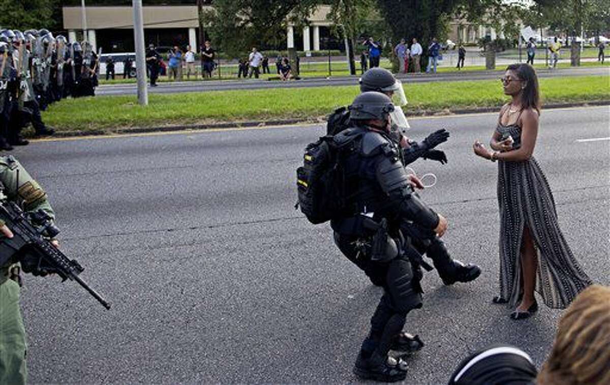 FILE In this Saturday, July 9, 2016 file photo, A protester is grabbed by police officers in riot gear after she refused to leave the motor way in front of the the Baton Rouge Police Department Headquarters in Baton Rouge, La. Police made nearly 200 arrests in Louisiana's capital city during weekend protests around the country in which people angry over police killings of young black men sought to block some major interstates. (AP Photo/Max Becherer)