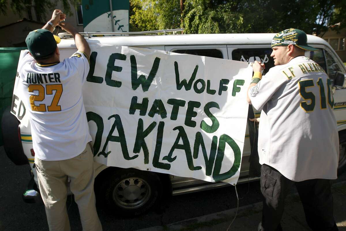 Jorge Leon (left) and Bobby Tselentis hang a banner critical of Oakland A's owner Lew Wolff outside a community meeting at Peralta Elementary School to discuss ballpark options in Oakland in 2010.