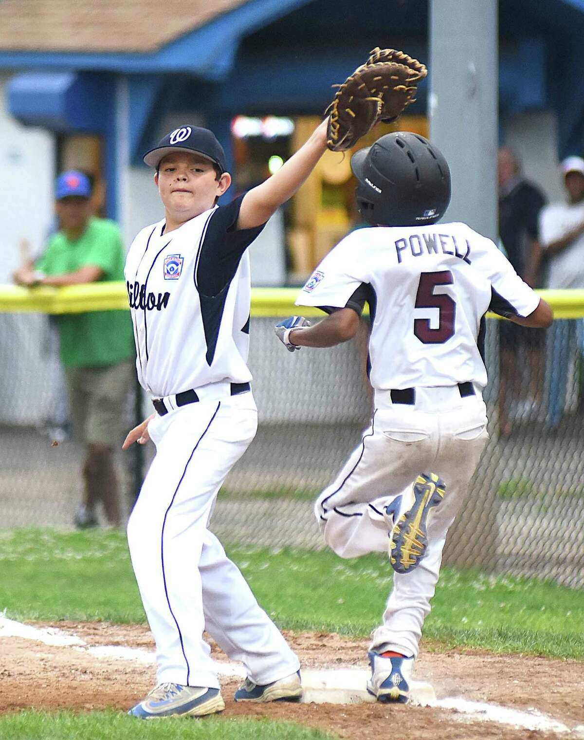 Wilton first baseman Alex Reyes, left, holds the bag with the ball in his glove at Stamford National runner Zach Powell hits first base during last week's District 1 11-year-old championship game.