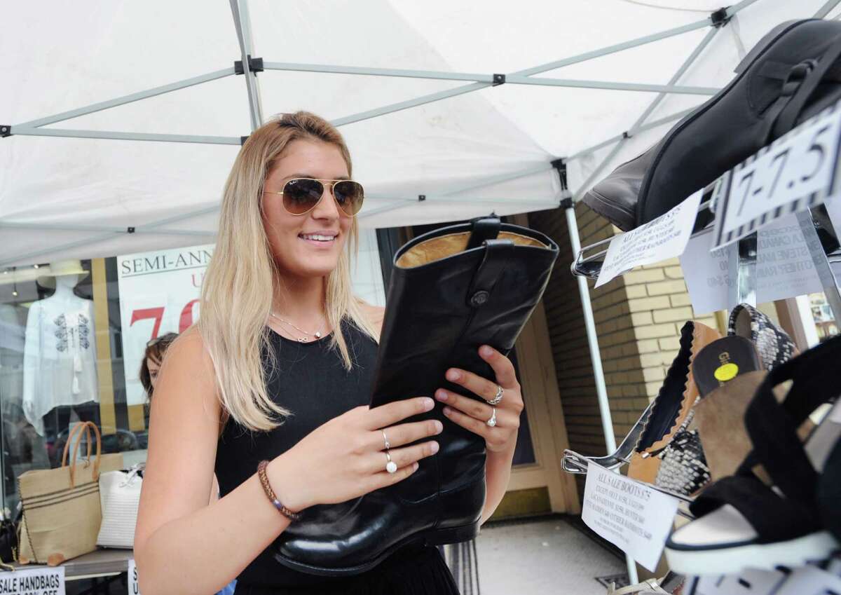 Valerie Sprovieri of Harrison, N.Y., shops for boots at Shoes 'n' More during the annual Sidewalk Sales organized by the Greenwich Chamber of Commerce on Greenwich Avenue, Greenwich, Conn., Thursday, July 14, 2016. According to the Greenwich Chamber of Commerce website, over 120 businesses are participating in the central Greenwich sales event that features merchants offering deep discounts on brand items under small tents placed outside their stores. The event runs from 10 a.m. to 6 p.m. on Friday and Saturday, and from 11 a.m. to 5 p.m. on Sunday, the final day of the sales.
