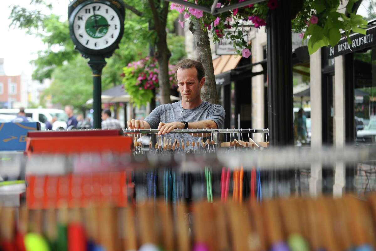 Troy Burk, owner of Fleet Feet Sports on Bedford Street, organizes a rack of clothes during the first day of the Downtown Sidewalk Sales Weekend on Friday.