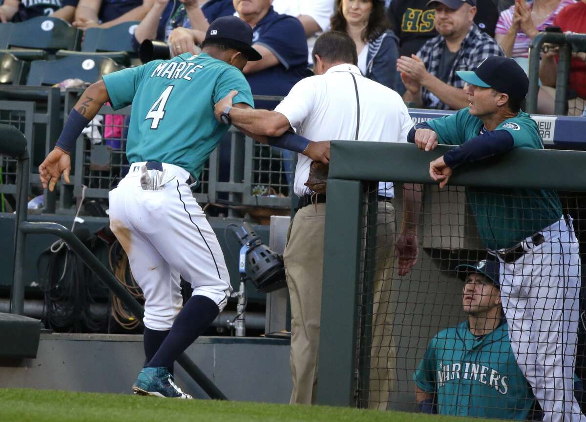 Seattle Mariners' Ketel Marte is helped into the dugout by Mariners trainer Rick Griffin as Marte leaves the baseball game at the start of the fourth inning against the Houston Astros, Friday, July 15, 2016, in Seattle. Marte was injured as he was tagged out sliding into third base in the third inning.