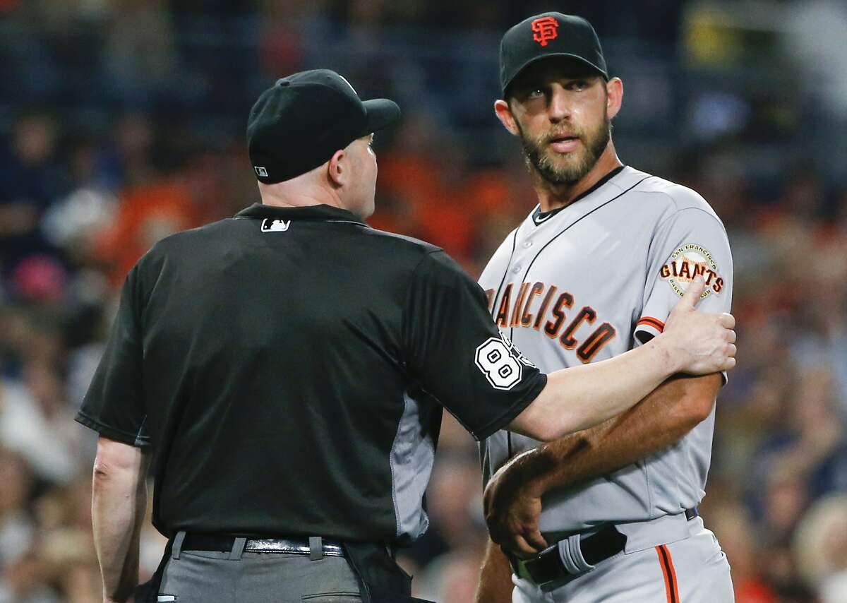 Home plate umpire Mike Estabrook puts a hand on the warm of San Francisco Giants pitcher Madison Bumgarner after the top half of the fifth inning of the Giants' baseball game against the San Diego Padres on Friday, July 15, 2016, in San Diego. (AP Photo/Lenny Ignelzi)