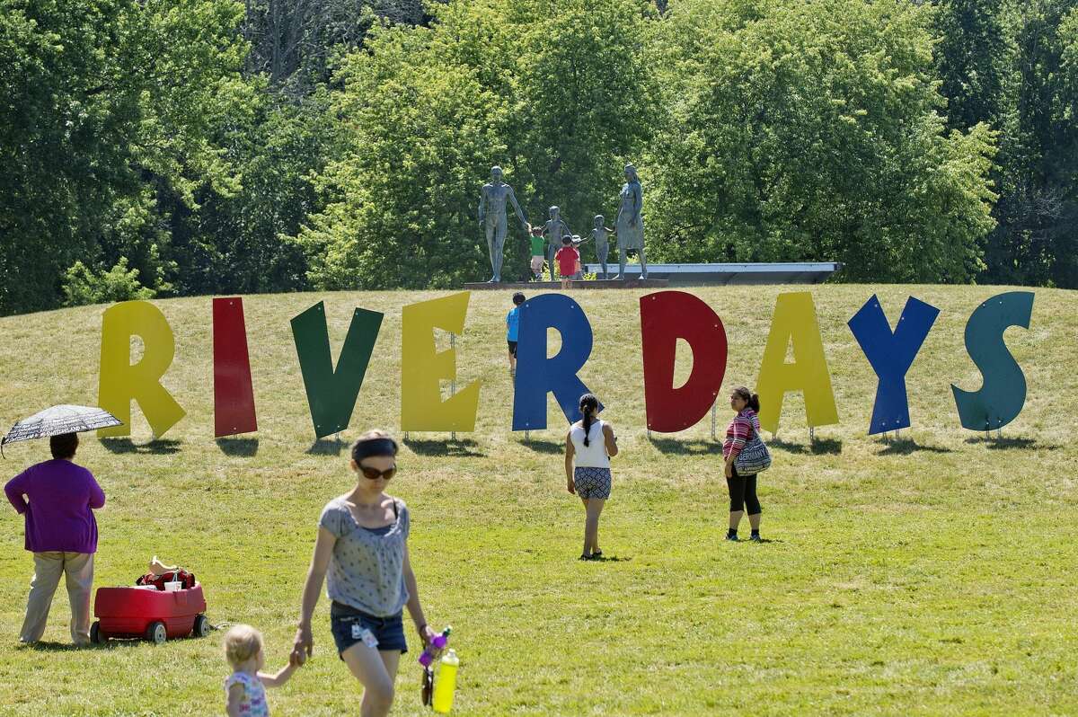File - Festival goers walk near a large sign reading 'River Days' during the festival at Chippewassee Park.