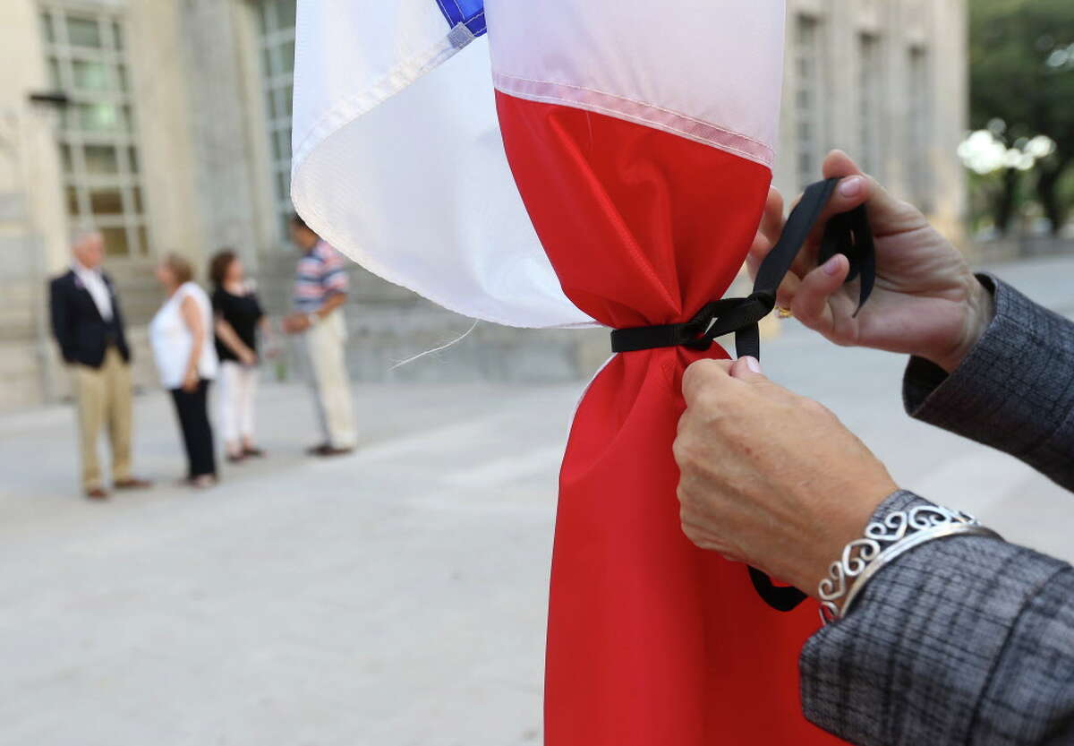 Ghislaine Thomsen ties a black ribbon around the French flag before a vigil for the victims of the Nice attacks, at Hermann Square, Saturday, July 16, 2016, in Houston.