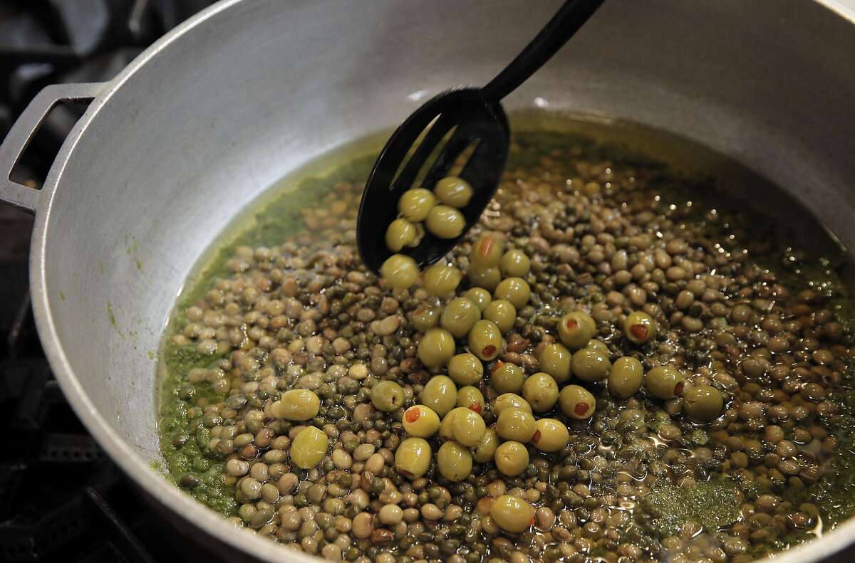 Olives added to the capers and sofrito as Christpher Caraballo makes arroz con gandules at the Puerto Rican restaurant, Borinquen, he run with his business partner Eric Rivera in the Fruitvale district of Oakland, Calif., on Sunday, July 17, 2016. Christopher Caraballo and Eric Rivera run a permanent pop-up in a convenience store that specializes in Puerto Rican food. They learned to cook these recipes by filming Christopher's mother on his iPhone, and specialize in arroz con gandules (rice with pigeon peas).