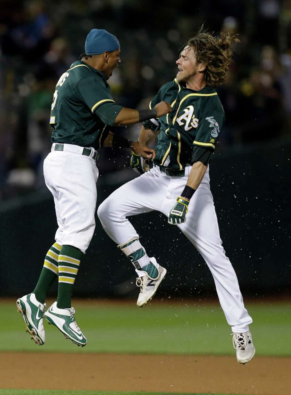 Oakland Athletics' Josh Reddick, right, celebrates with Khris Davis after making the game winning hit in the tenth inning of a baseball game against the Houston Astros Tuesday, July 19, 2016, in Oakland, Calif. (AP Photo/Ben Margot)