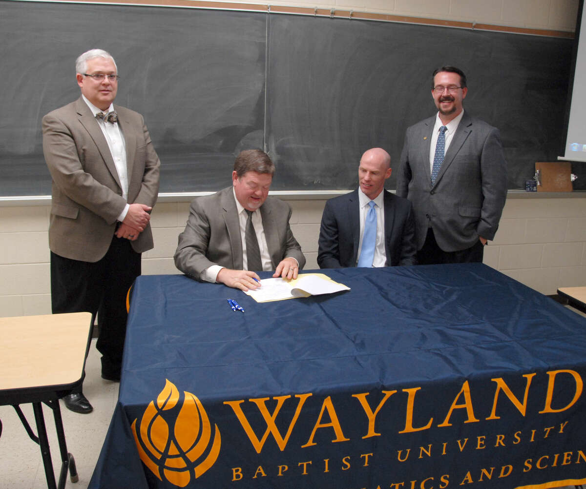 Wayland Baptist University Associate Vice President Dr. Stan Demerritt (standing, left) and Dean of the School of Mathematics and Sciences Dr. Scott Franklin (right) look on as WBU Executive Vice President and Provost Dr. Bobby Hall and West Texas A&M University Associate Dean of the School of Engineering Dr. Matt Jackson sign an agreement between the schools that will make it possible for students to earn dual degrees in math and engineering.