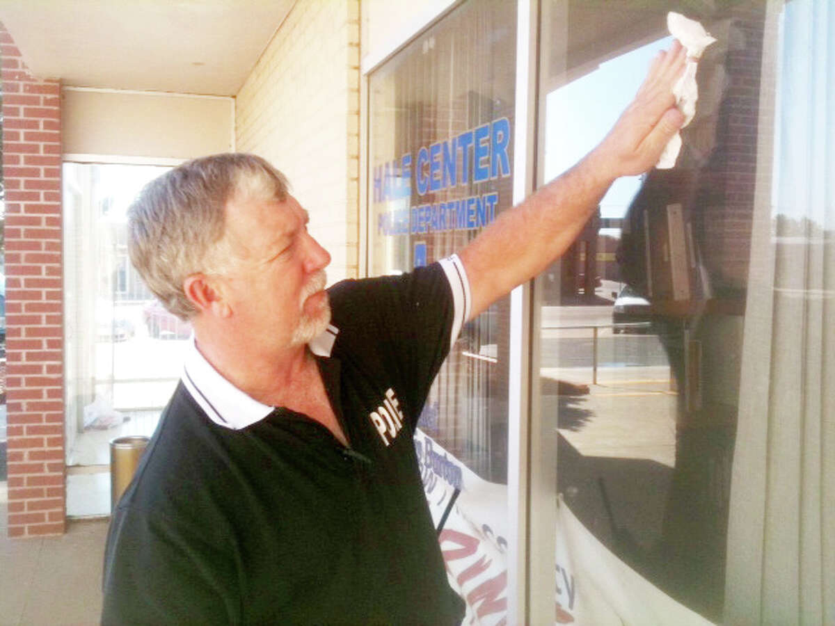 Hale Center Police Chief Dennis Burton cleans the windows at Hale Center City Hall/Police Department where, beginning Sept. 1, Burton plans to post the city's warrant list. More than 250 individuals have outstanding traffic tickets and unpaid fines.