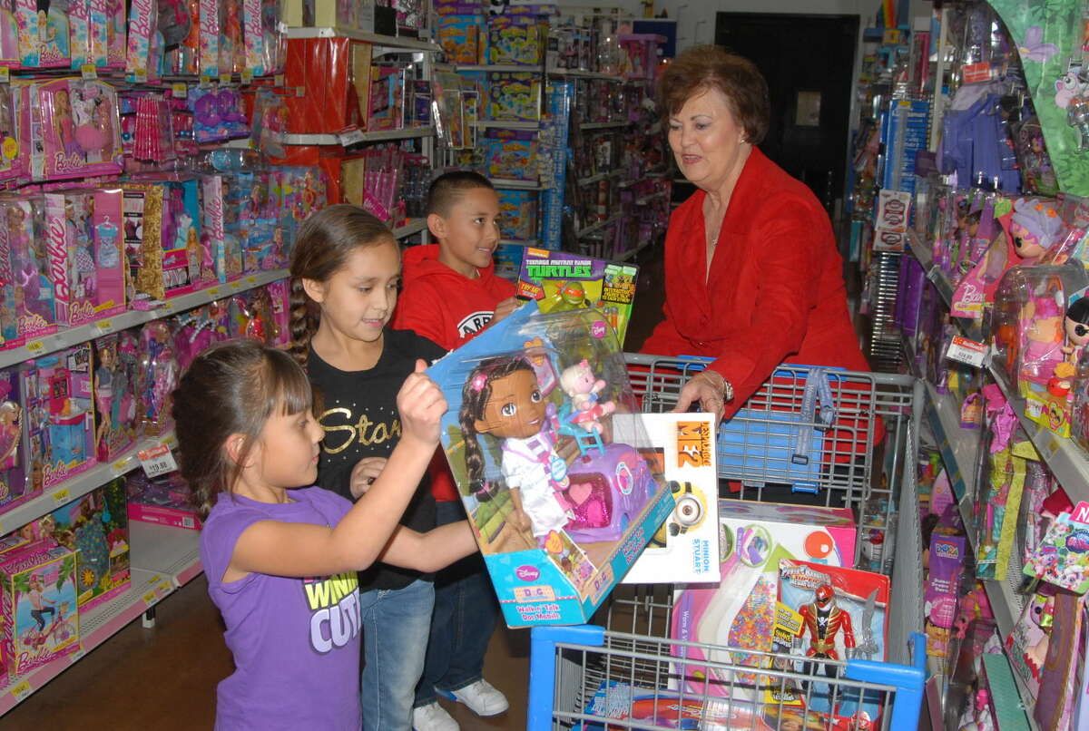 Aubrie Rogers and Layla Juarez fill up the shopping cart, while Devin Rogers hands Crisis Center of the Plains director Kay Harris a brand new toy during a Christmas shopping spree that will benefit the center.