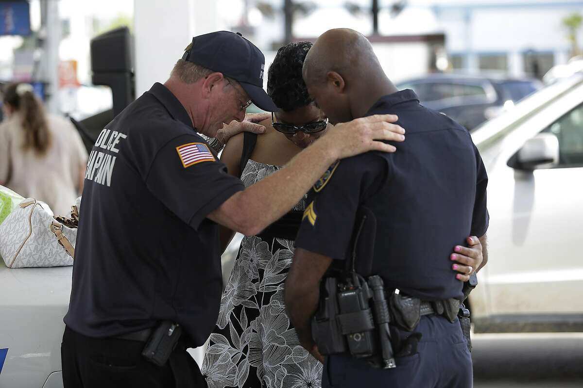 BATON ROUGE, LA - JULY 19: Millville, New Jersey police chaplain Bob Ossler (L) prays with Baton Rouge Police Department Corporal Trina Dorsey (C) and her brother Corporal Joseph Keller near a makeshift memorial for three police officers on July 19, 2016 in Baton Rouge, Louisiana. Three police officers were killed and several others wounded along Airline Highway Sunday when Gavin Long, who traveled from Kansas City, Missouri, ambushed the law enforcement officers. (Photo by Joshua Lott/Getty Images)