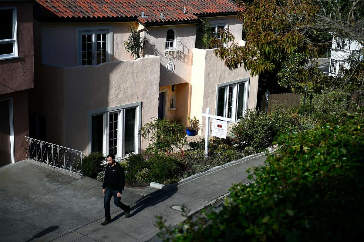 A passerby walks by a home for sale on Magellan Ave on Wednesday, July 20, 2016 in San Francisco, California.