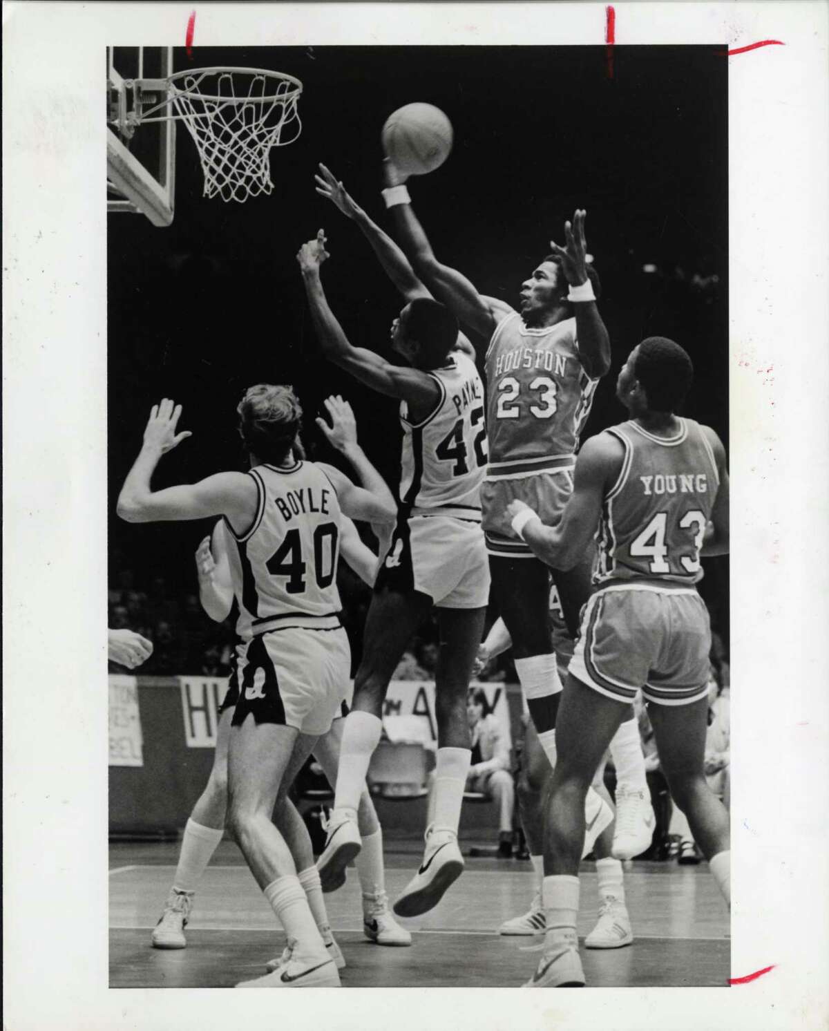 12/19/1981 - UH Cougars forward Clyde Drexler rebounds over Iowa at Hofheinz Pavilion. The Cougars went on to win over Iowa 62-52. HOUCHRON CAPTION (12/21/1981): Clyde Drexler (23) leaps over Iowa's Michael Payne to grab one of his 18 rebounds in the University of Houston Cougars' victory over fifth-ranked Iowa Saturday night.