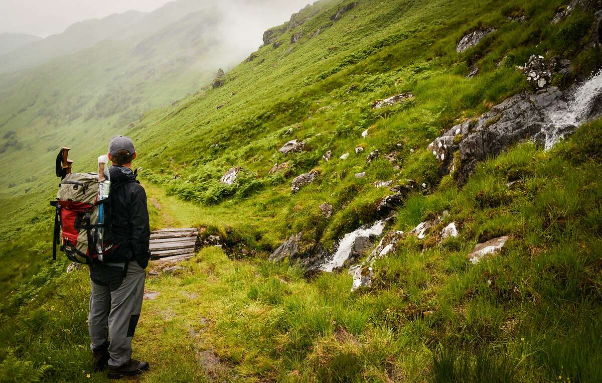 Hiking the misty trail through the Scottish Highlands, dotted with waterfalls.