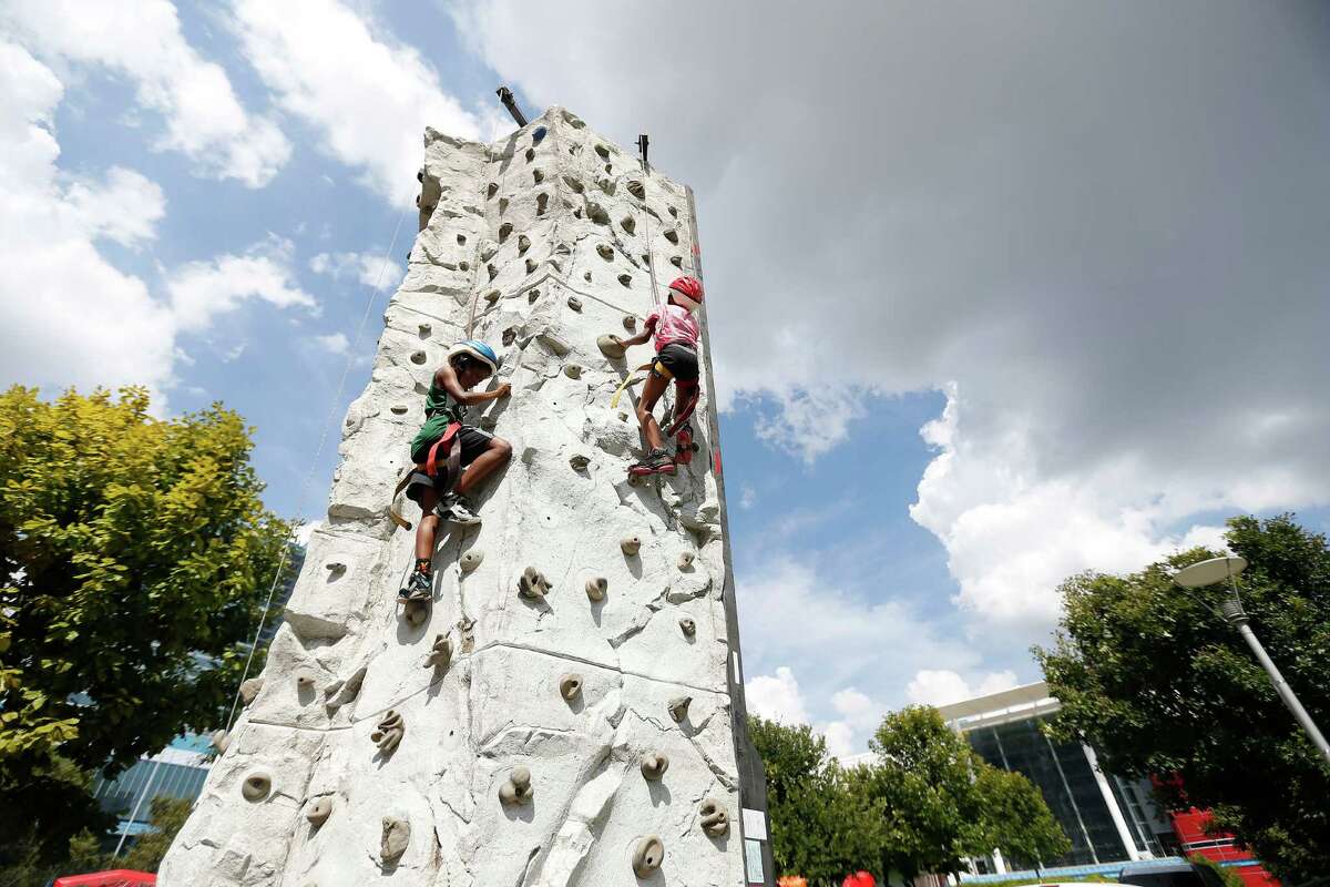 Kids climb a rock wall during rapper Trae tha Truth's third annual Trae Day, with free backpacks, immunizations for kids at Discovery Green, Friday, July 22, 2016, in Houston.