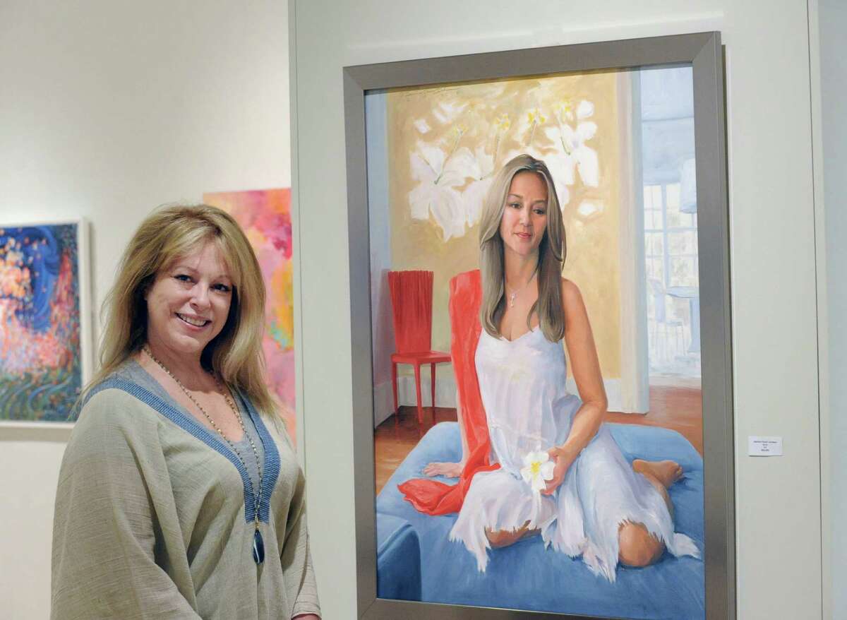 Jeanine C. Jackson, president of the Connecticut Society of Portrait Artists, next to her oil painting titled “Nora” in the Flinn Gallery at Greenwich Library on Thursday. Jackson said the work is a tribute to motherhood.