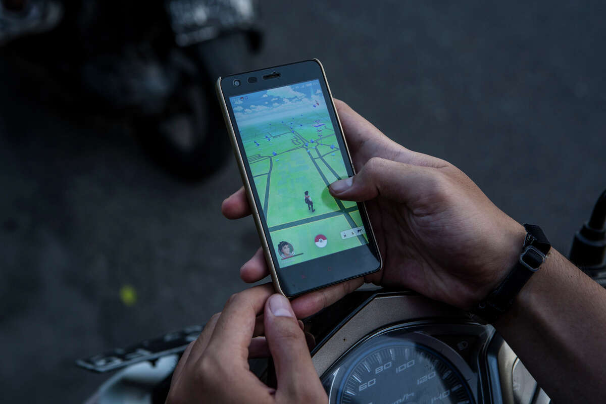 YOGYAKARTA, INDONESIA - JULY 24: A motorcyclist, plays Pokemon Go game on his smartphone on July 24, 2016 in Yogyakarta, Indonesia. "Pokemon Go," which uses Google Maps and a smartphone has been a smash-hit in countries where it is available and already popular in Indonesia even though it has not been officially released. Indonesians have been downloading the game by using a proxy location which gives them access to app stores of other countries as security officials have voiced worries that the game could pose a security threat. (Photo by Ulet Ifansasti/Getty Images)