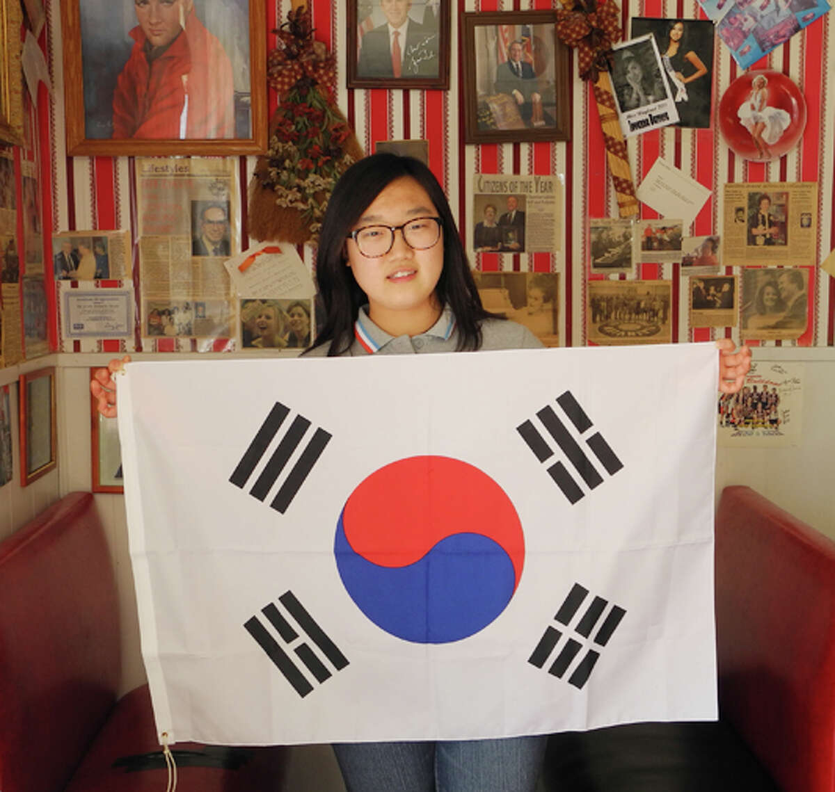 Surrounded by American cultural icons at the Roaring 50s café in Plainview, South Korean exchange student Haeun Kim holds up her country’s flag. The yingyang symbol stands for perfect balance, and each of the four trigrams in the corners have a different meaning.