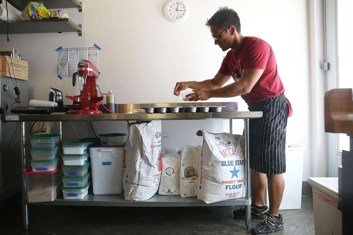 Pastry chef/mochi maker Sam Butarbutar tops Hawaiian Mochi batter with sesame seeds in his kitchen at Catahoula Coffee on Friday, July 22, 2016, in Berkeley, Calif.