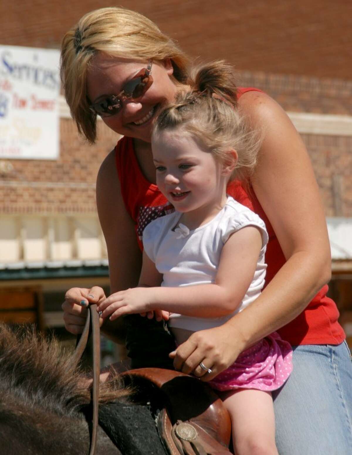 Three-year-old Cheyenne Patterson gets a ride from her friend, Julie Elbert during Saturday's bar-None Rodeo Parade in Plainview.