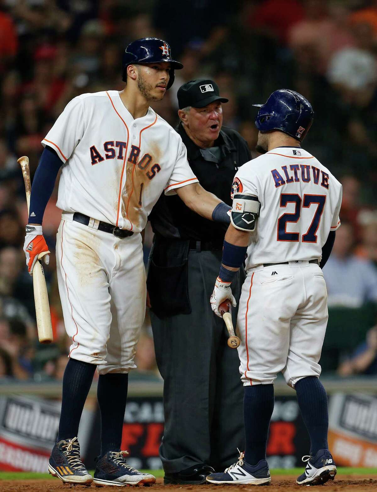 Carlos Correa, left, tries to separate Jose Altuve from plate umpire Dana DeMuth after Altuve was called out on strikes in the eighth inning.