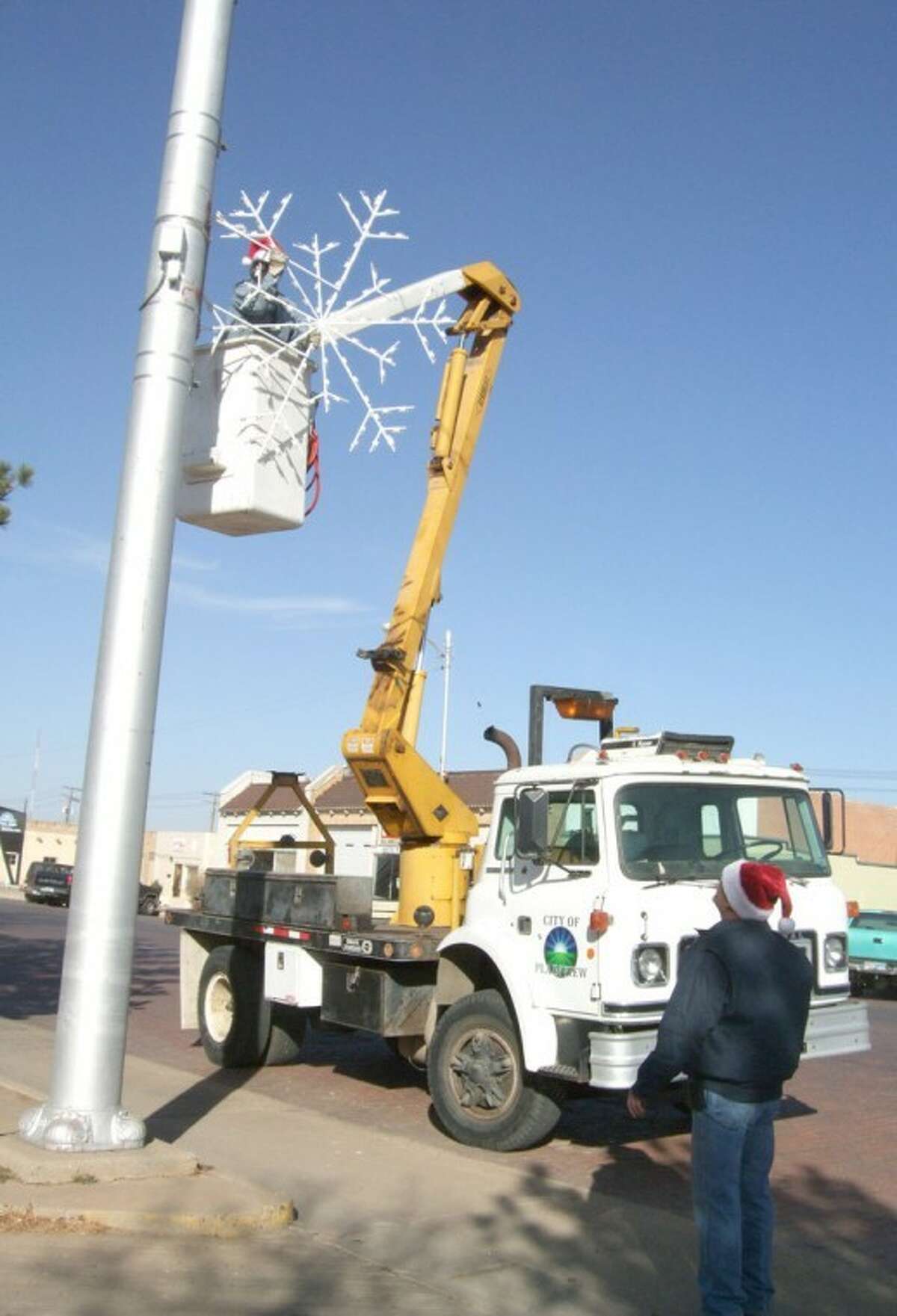 City of Plainview employees Felix Ruiz (on cherry picker) and Richard Alvis work Monday putting up new Christmas lights. About 40 6-foot-tall snowflake lights are going up on Broadway, Ash and Sixth streets. The lights — valued at more than $10,000 — were purchased at a discounted price during the off-season early this year.