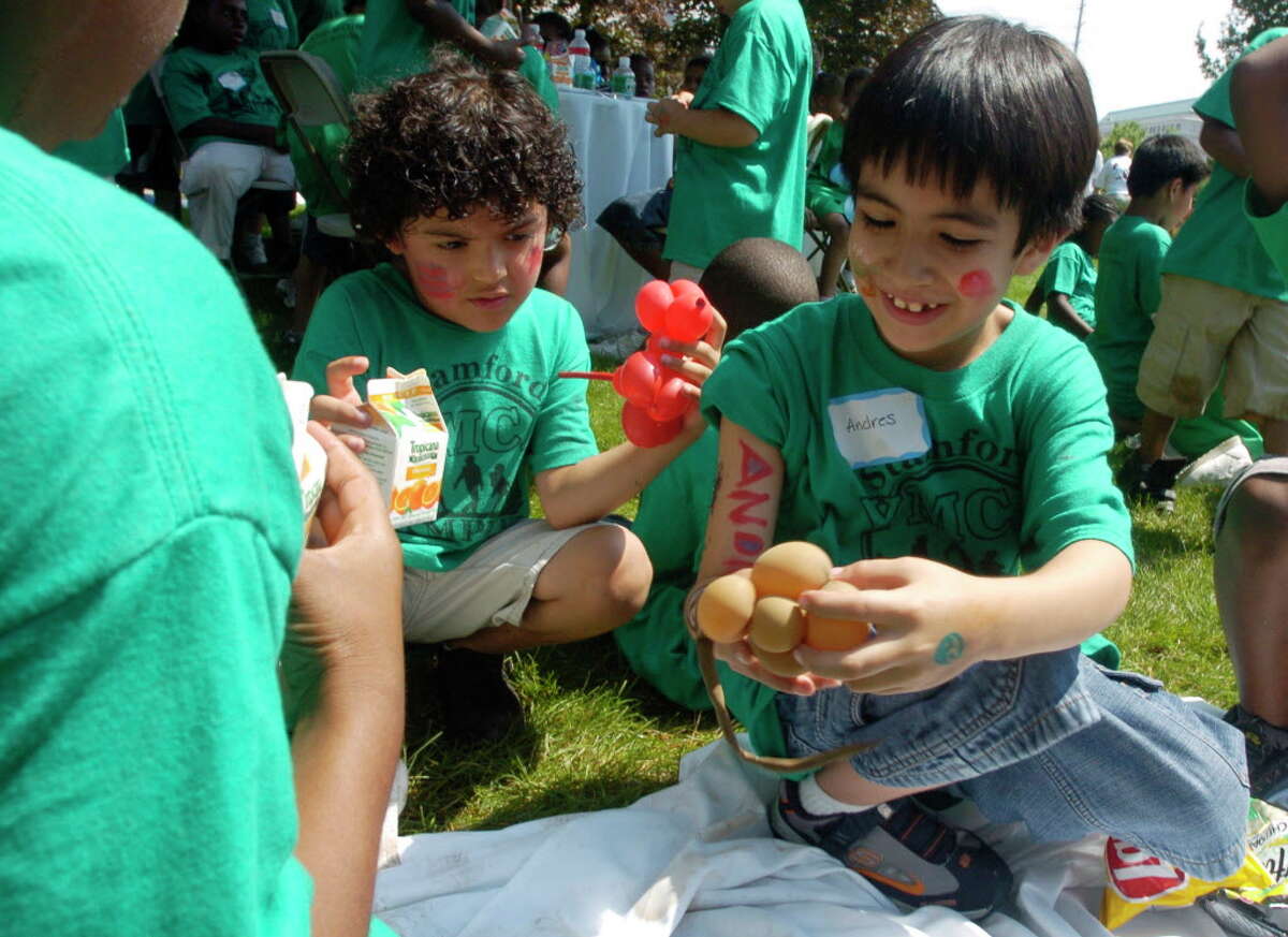 Stamford_071906_ (L to R) Elvis Gomez, 6, and Andres Oyola, 7, join other campers from the Stamford YMCA and the Yerwood Center at a carnival theme field day at the UBS Human Resources Volunteer Day. The two boys were from the YMCA World of Wonders Camp. Kathleen O'Rourke/Staff photo