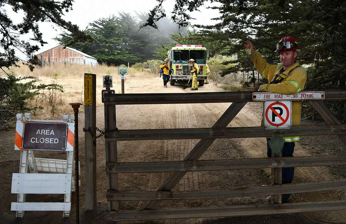 Tyler Mortensen (R) of Santa Clara County Fire Dept. blocks an entrance to Garrapata State Park near Carmel California on July 28, 2016. Scorching more than 27,000 acres, the Soberanes Fire has taken a toll on local businesses and caused multiple closures at state parks.