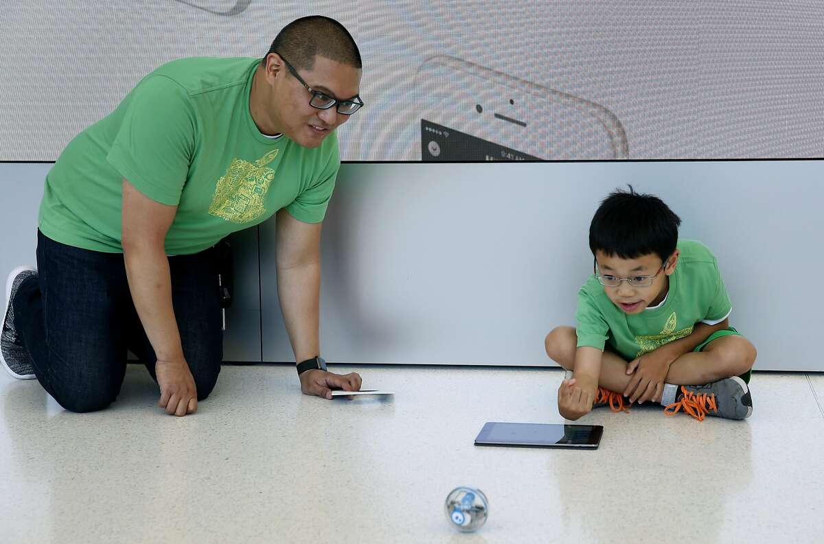Alvin Viray encourages Tom Lee, 9, while he learns how to program and control a Sphero robotic ball at an Apple youth coding class in San Francisco, Calif. on Thursday, July 28, 2016.