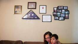 Sara Mata holds her son Jeremiah Garcia, 4, on the couch at their home in Laredo, Texas on July 26, 2016.  Above them hang reminders of Mata's husband, Manuel Garza, who was a veteran who committed suicide in the Fall of 2015 after struggling with PTSD from doing two tours in Iraq.  "He was everything I never thought I could have," Sara Mata said.